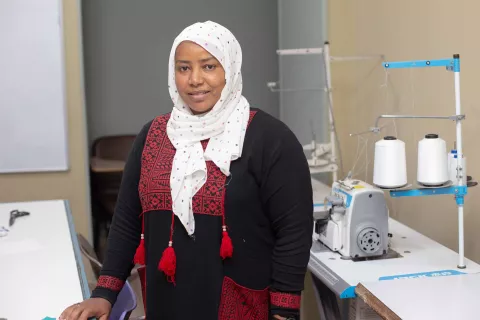 Image of a female worker standing in front of a sewing machine